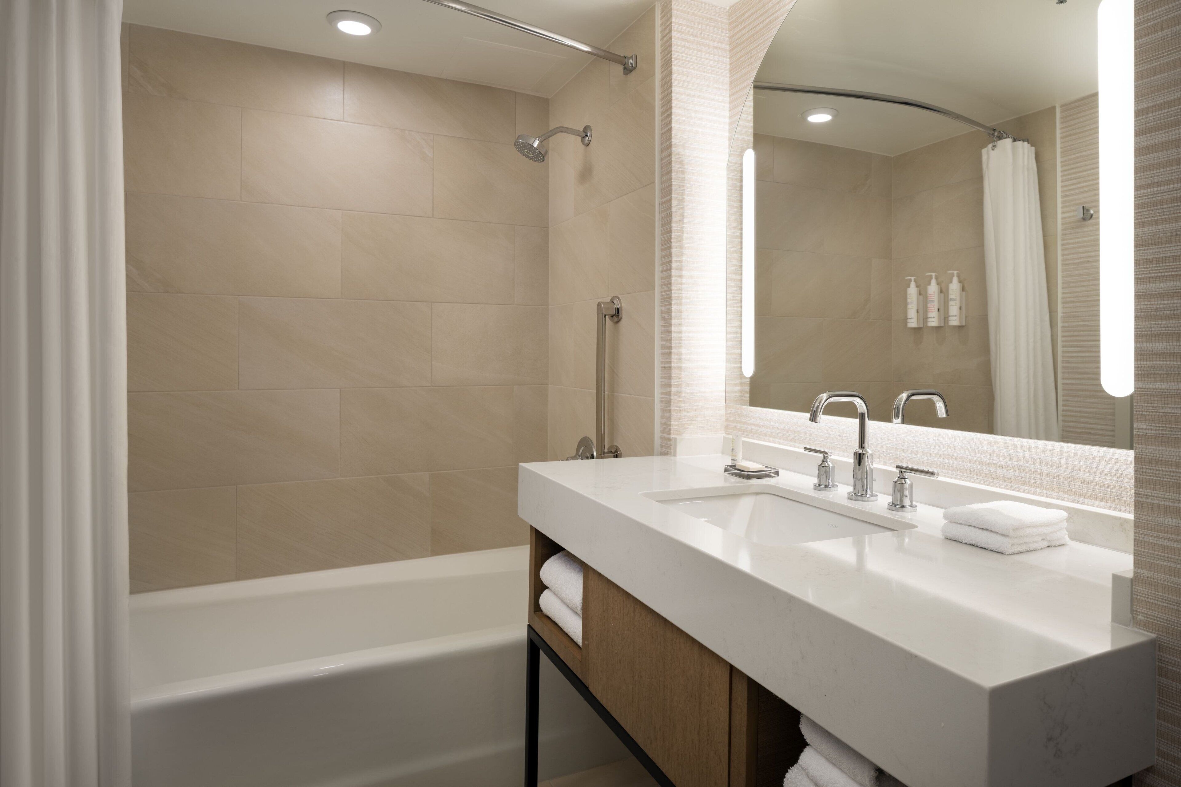 Un baño moderno con bañera, un espejo grande y un lavabo con mueble.
