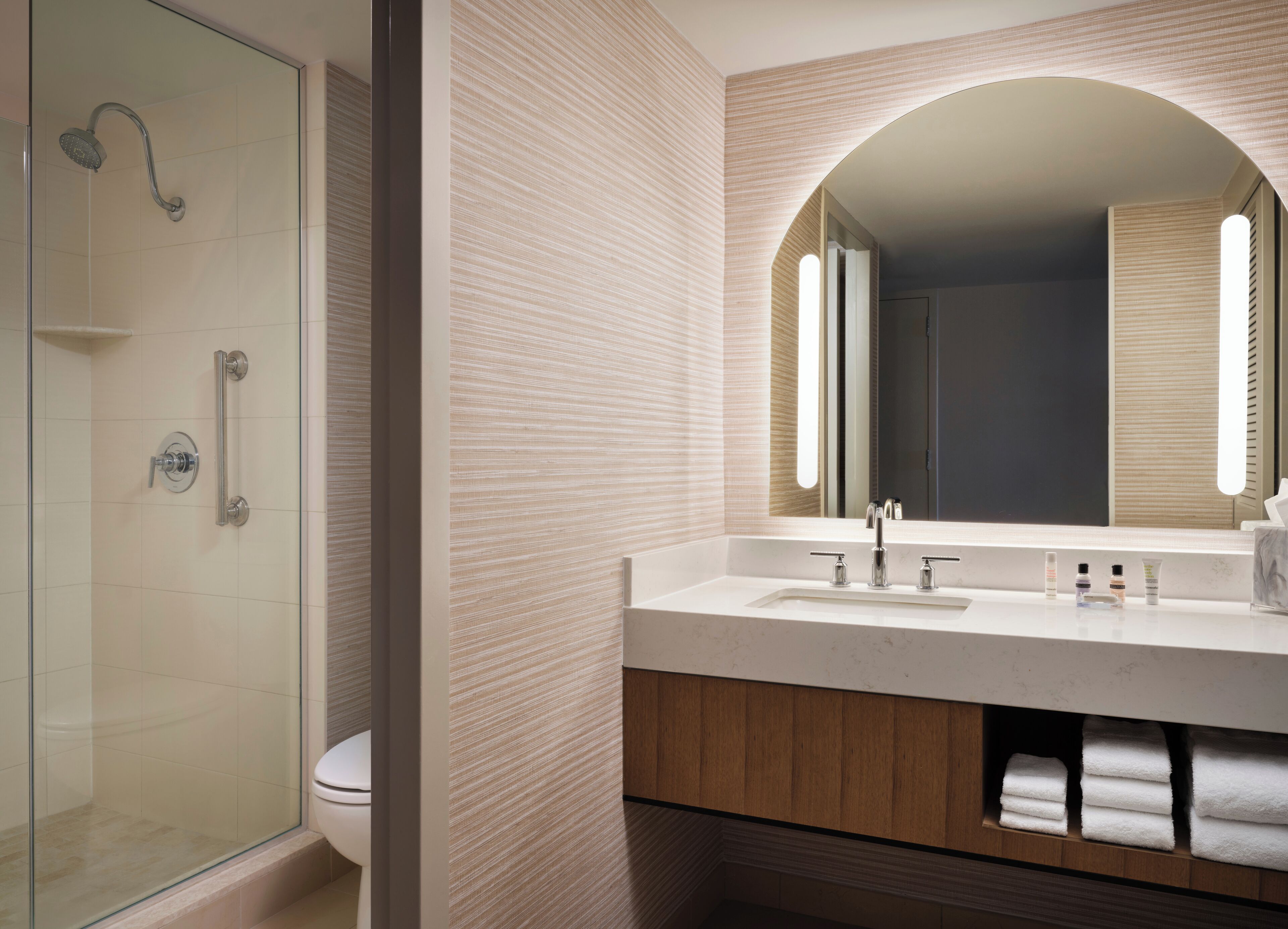A modern bathroom with a glass shower enclosure, a vanity with a mirror, and a towel rack.
