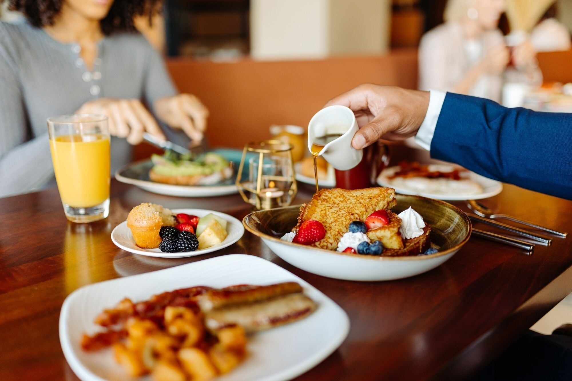 Un desayuno con una variedad de platos, incluyendo tortitas, frutas y tocino.