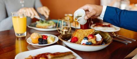 Un desayuno con una variedad de platos, incluyendo tortitas, frutas y tocino.