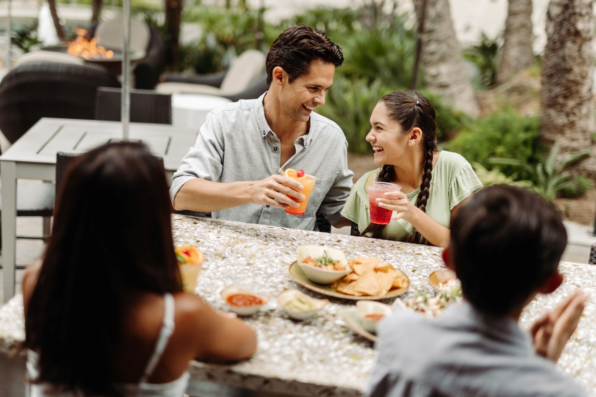 Un grupo de personas cenando al aire libre en una mesa con diversos platos y bebidas.