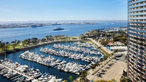 Un puerto deportivo con numerosas embarcaciones amarradas, un gran barco al fondo y un edificio moderno con balcones.