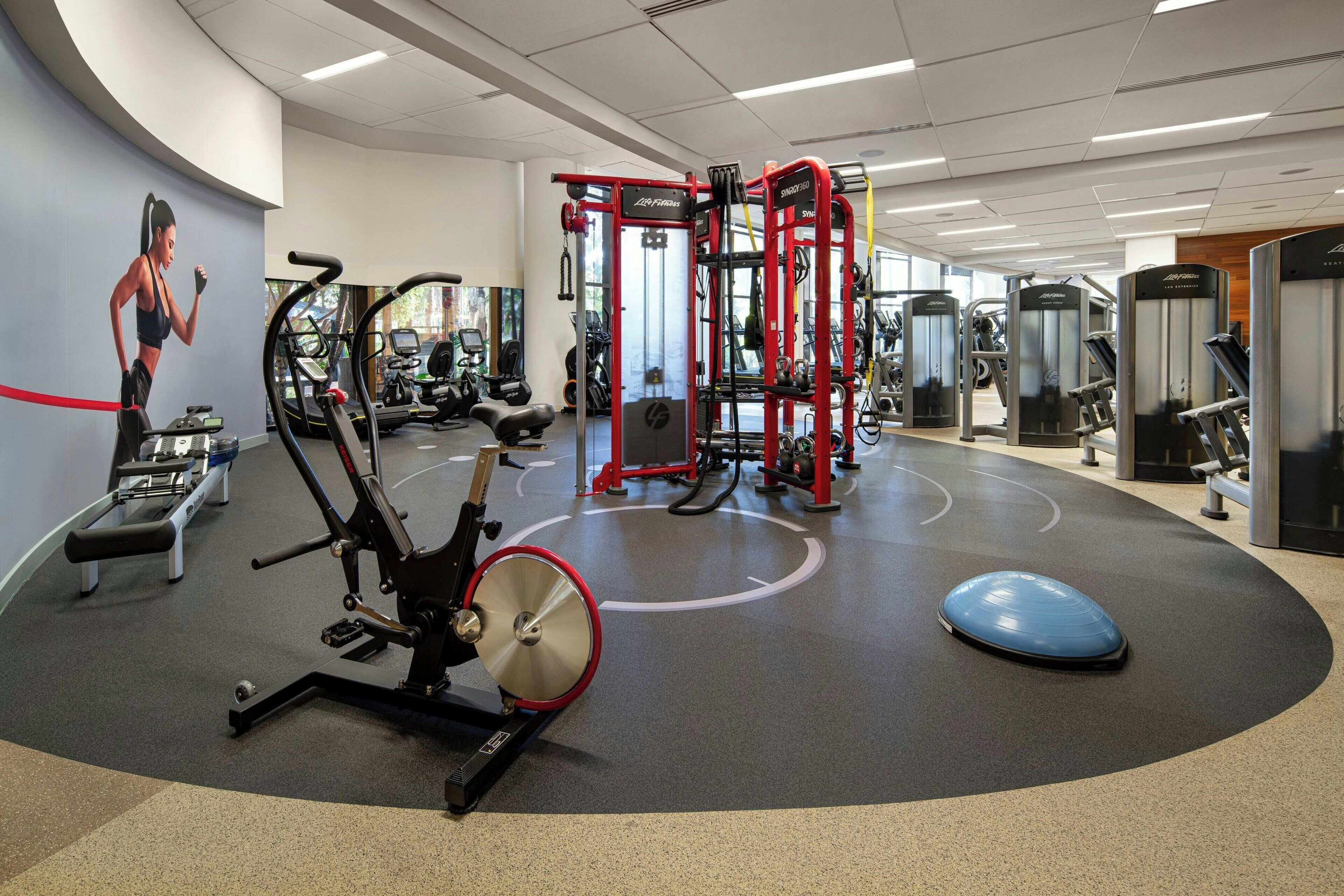 A gym with cardio machines, weightlifting equipment, and a large mirror.