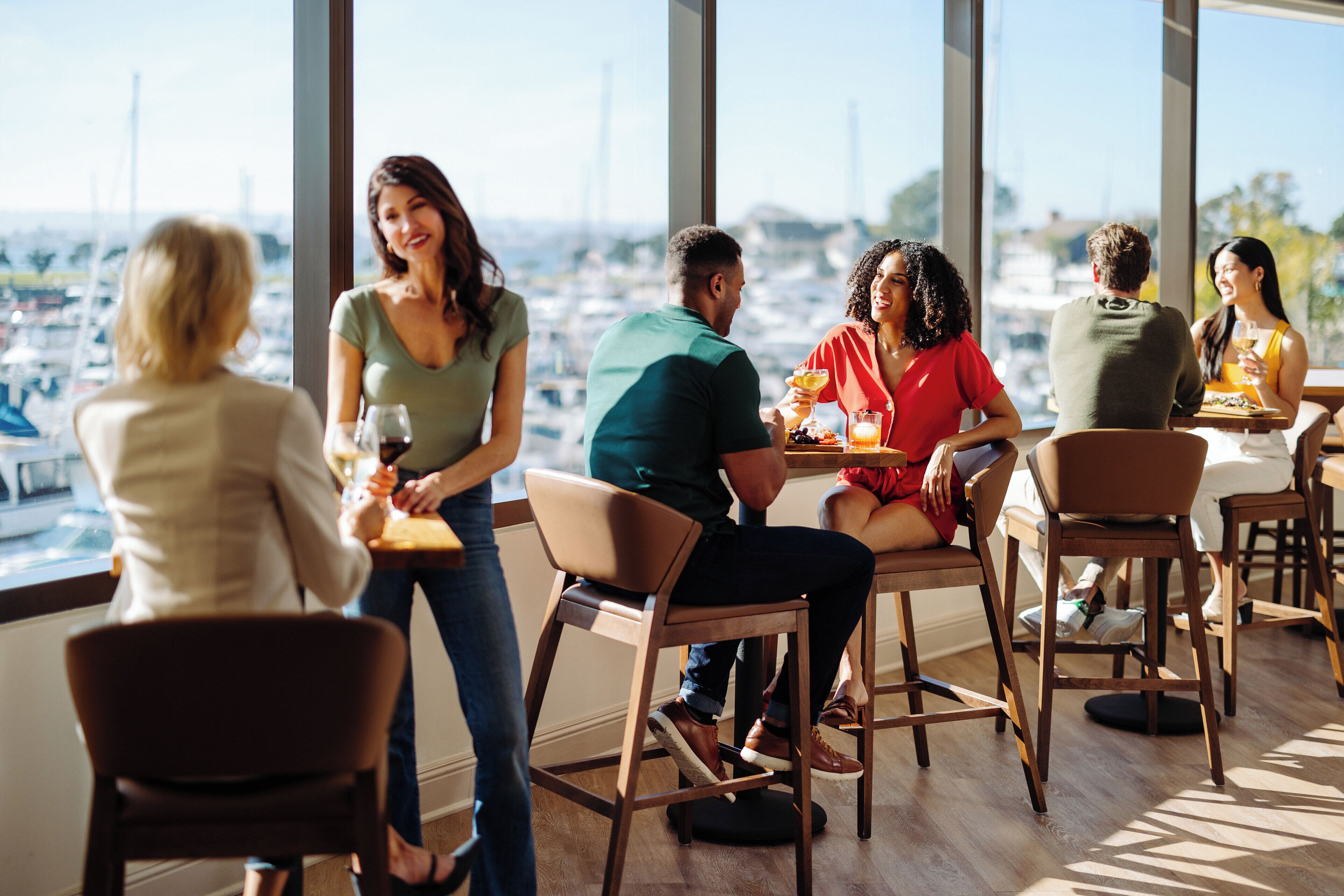 A group of people dining at a restaurant with a view of the marina.