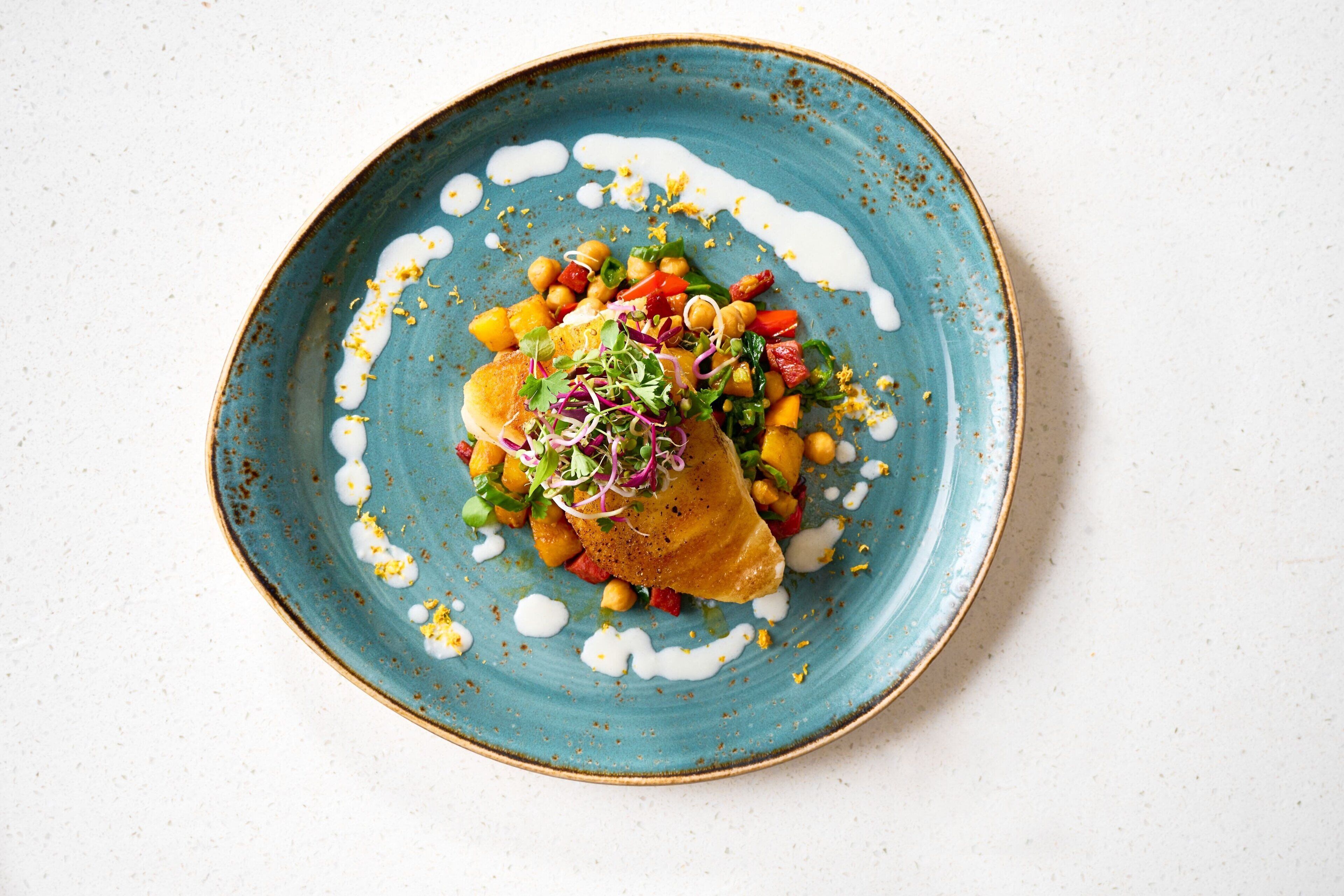 A plate of food with a variety of vegetables and chickpeas, served on a blue ceramic plate.