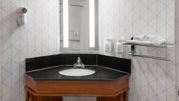 A bathroom with a black countertop sink, a mirror, a towel rack, and a hair dryer mounted on the wall.