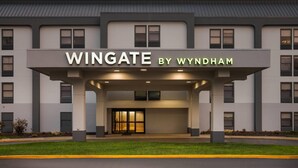 Un edificio con un letrero que dice 'Wingate by Wyndham' y una entrada cubierta.