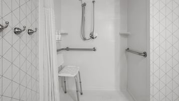A shower area with grab bars, a shower chair, and a handheld showerhead.
