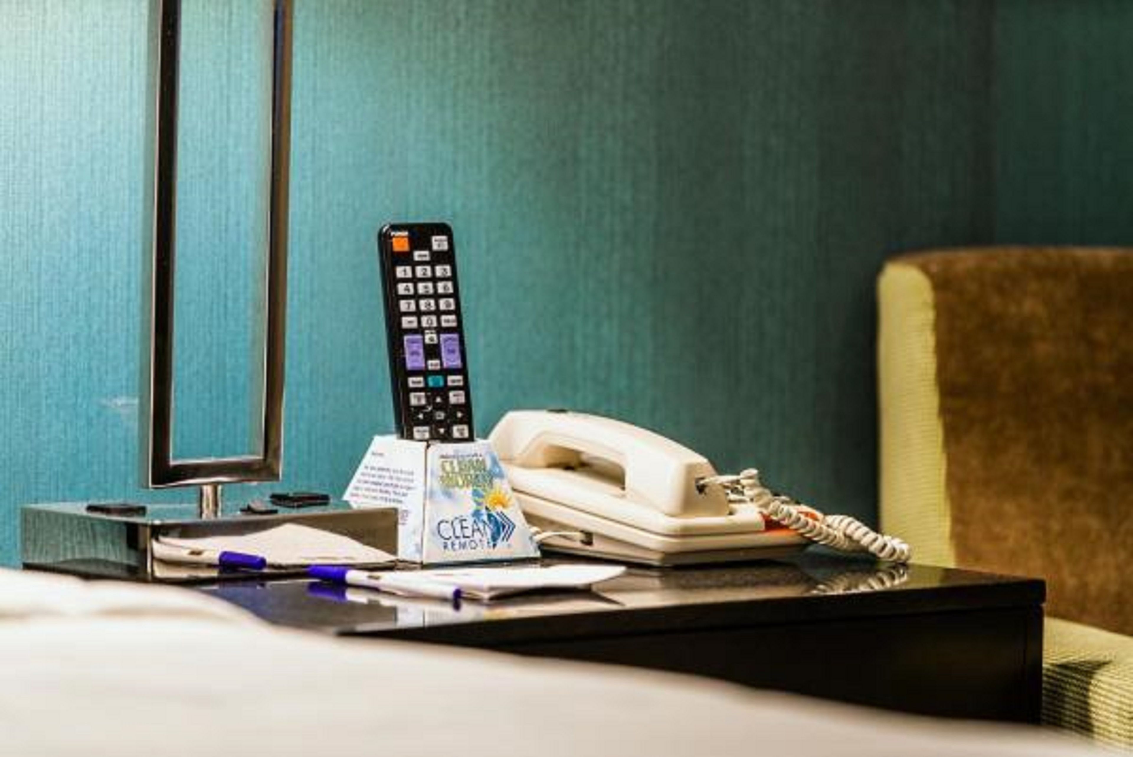 Een hotelkamer met een bureau, telefoon, afstandsbediening en een bordje 'Schone afstandsbediening'.