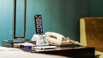 A hotel room with a desk, a telephone, a remote control, and a 'Clean Remote' sign.