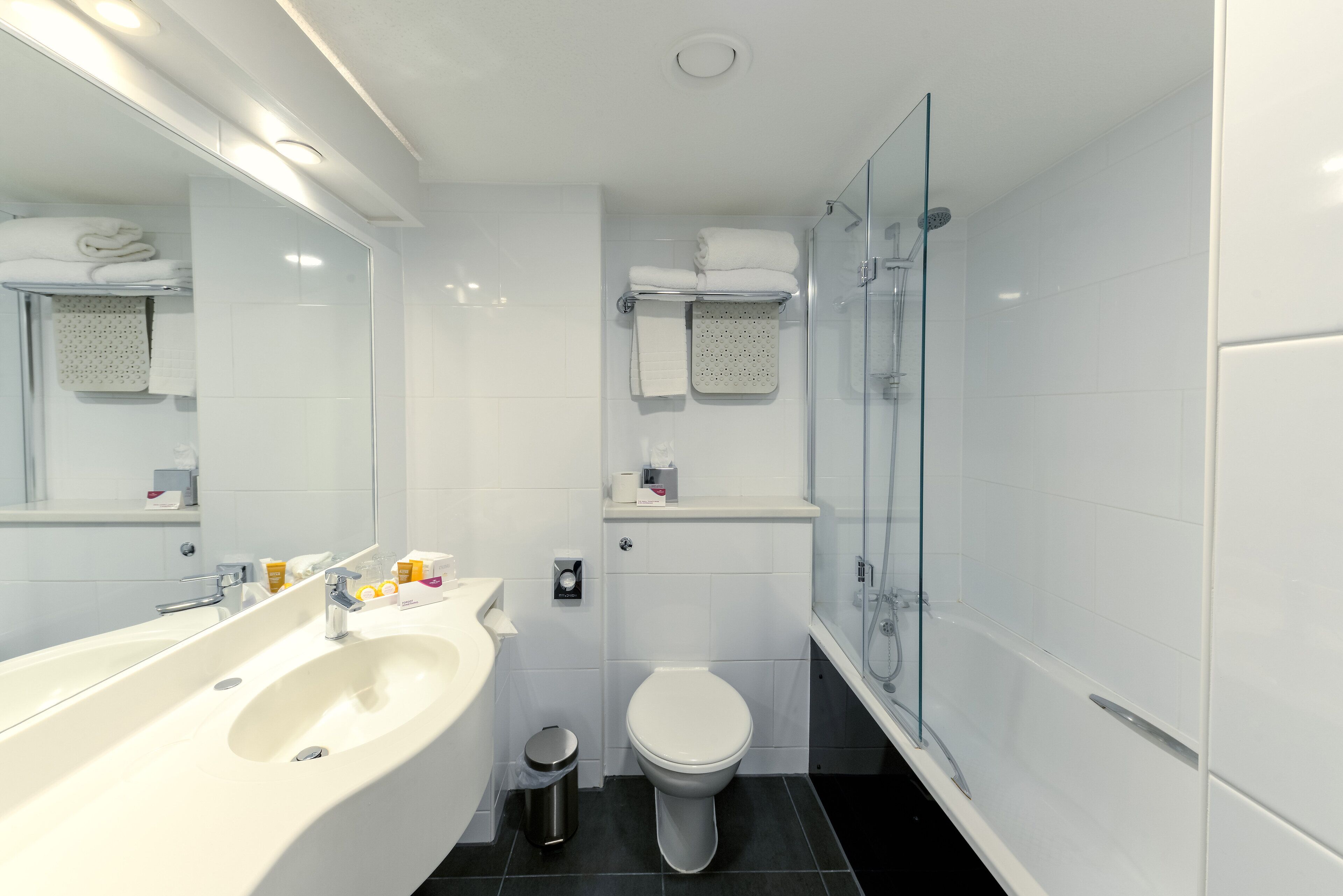 A modern bathroom with a large sink, toilet, and glass shower enclosure.