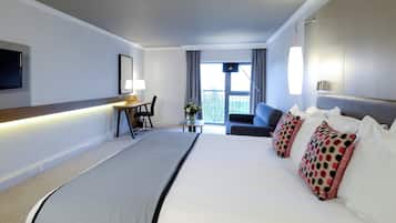 A hotel room with a bed, a desk, a chair, a TV, and a window with curtains.