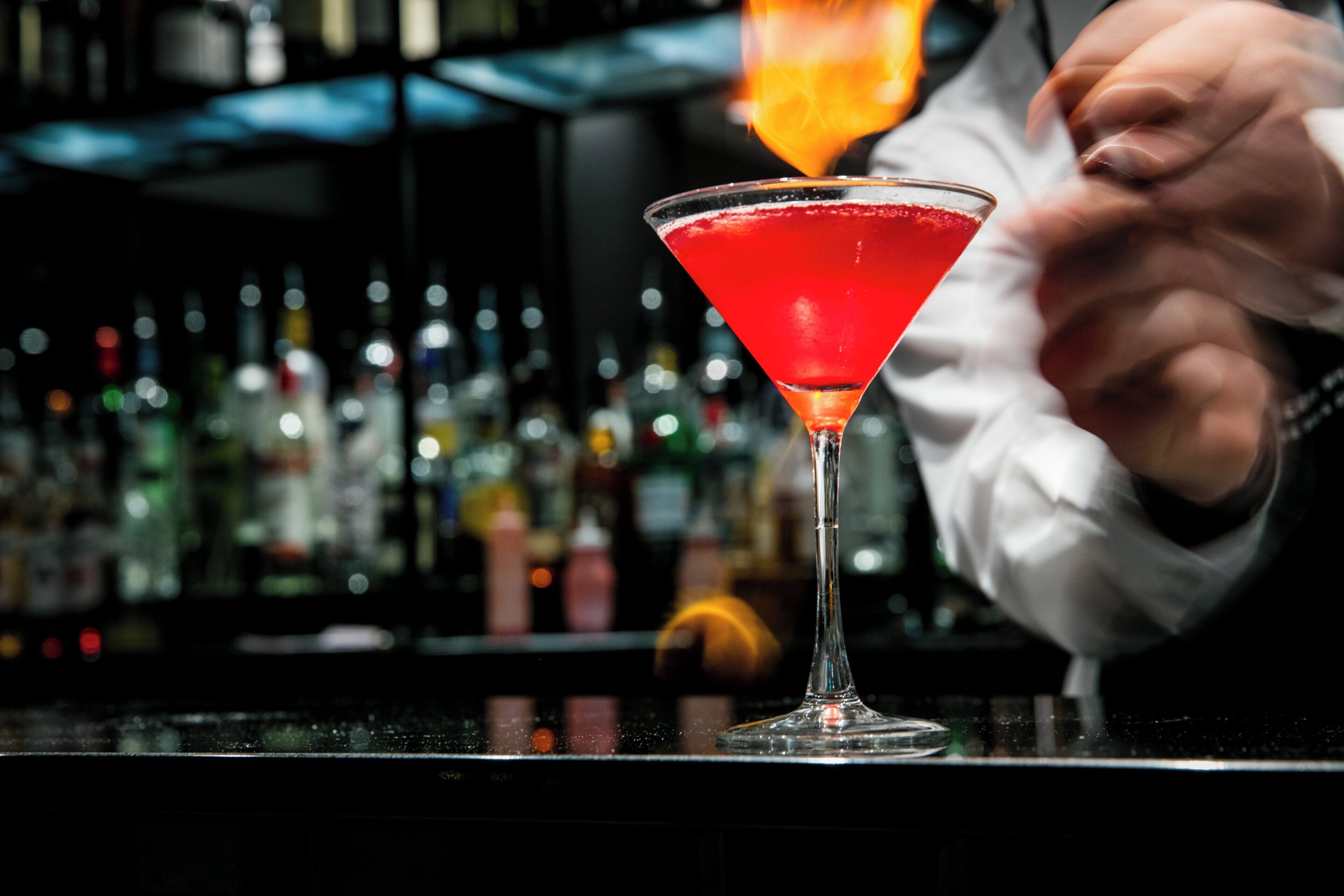 A bartender preparing a cocktail in a martini glass.