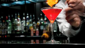 A bartender preparing a cocktail in a martini glass.