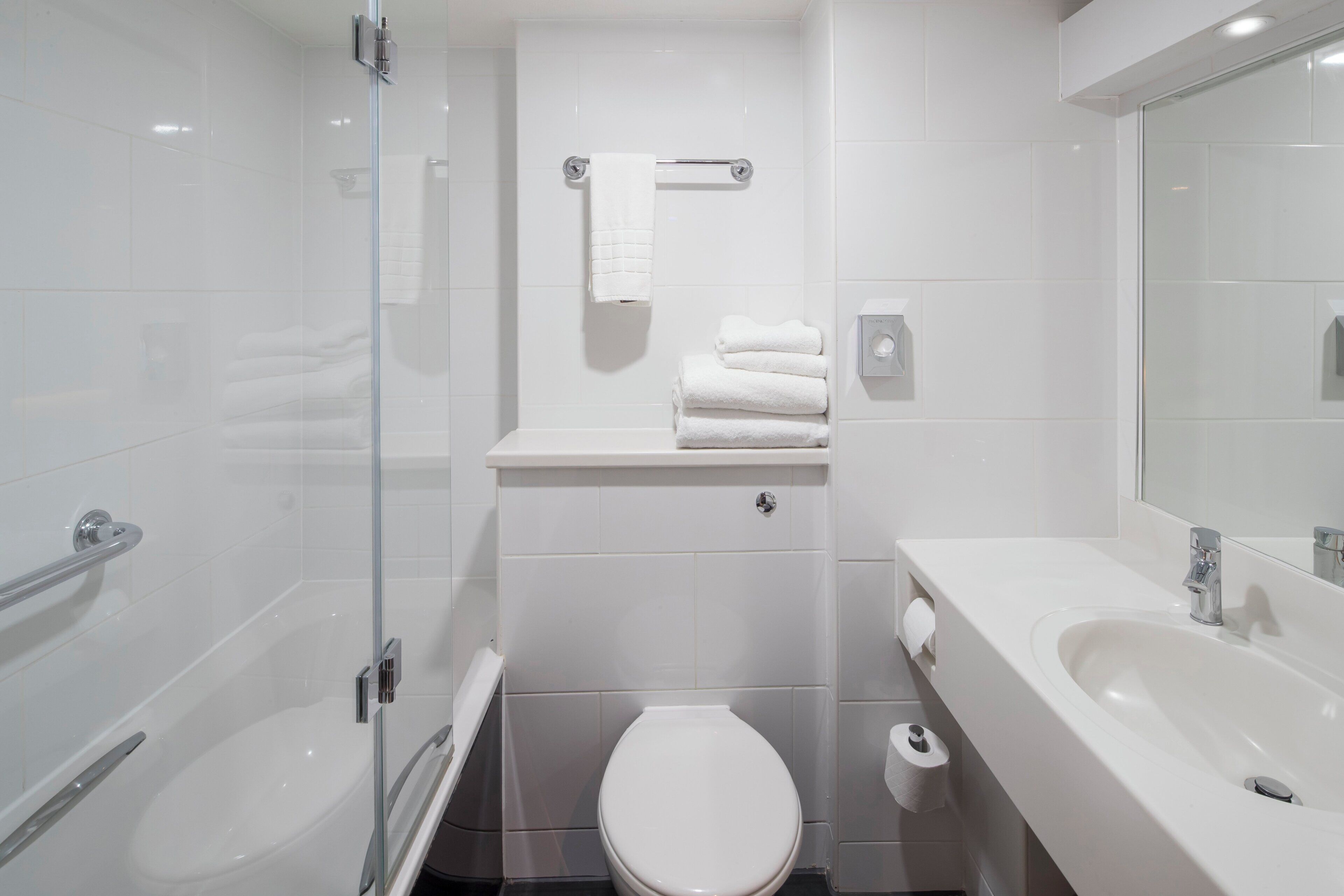 Un bagno moderno con doccia vetrata, un water bianco e un lavabo con specchio.