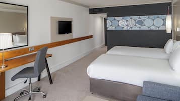 Een hotelkamer met een bed, een bureau, een stoel, een televisie en een behang met een patroon.