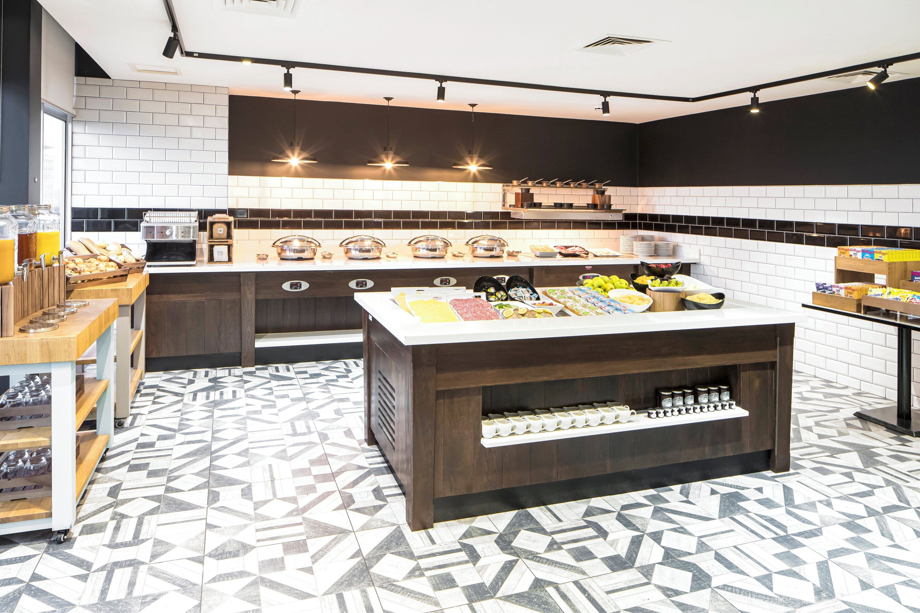 A modern kitchen with a central island, a coffee machine, and a variety of food items on display.