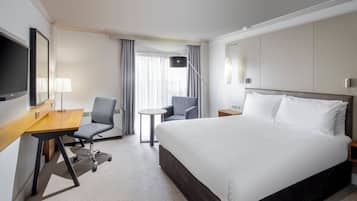 Habitación de hotel con cama, escritorio, silla y televisión.