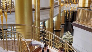 A grand staircase with golden railings and wooden steps, leading to an upper floor. - Dusit Thani Manila (Makati)