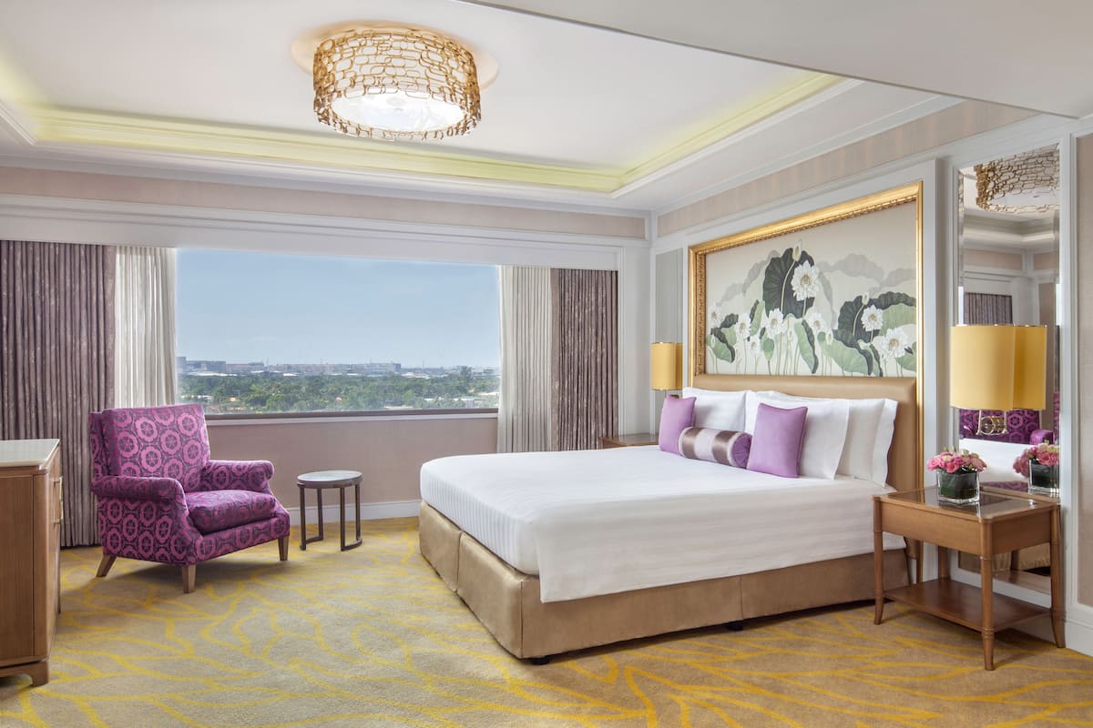 Una habitación de hotel con una cama grande, una silla, una mesita y vistas a la ciudad.