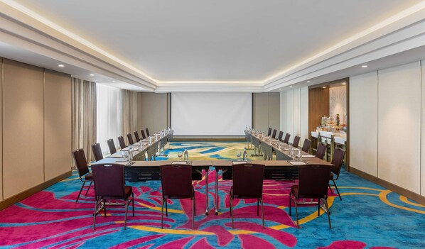 Un salón de conferencias con una larga mesa, sillas y piso alfombrado.