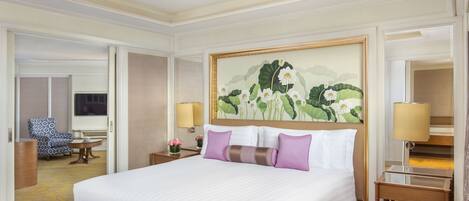 Una habitación de hotel con una cama grande, una mesita de noche con lámpara, una pequeña mesa con flores y una silla.