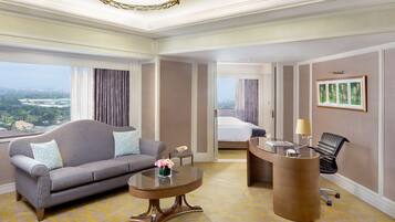 Ein Hotelzimmer mit einer Couch, einem Schreibtisch, einem Bett und Blick auf die Stadt.