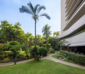 A well-maintained garden with palm trees, a curved pathway, and a building with outdoor seating.