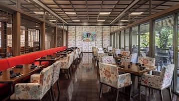 Un restaurante con una barra larga, asientos rojos y sillas con motivos florales.