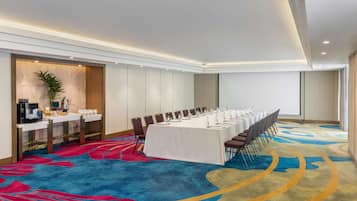 A conference room with a long table, chairs, and a coffee station.