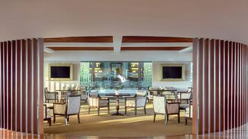 A spacious lobby with a central seating area, a large window, and a decorative wall with vertical slats.