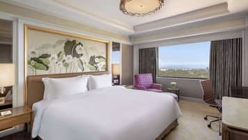 Habitación de hotel con una cama grande, una silla, un escritorio y vistas a la ciudad.