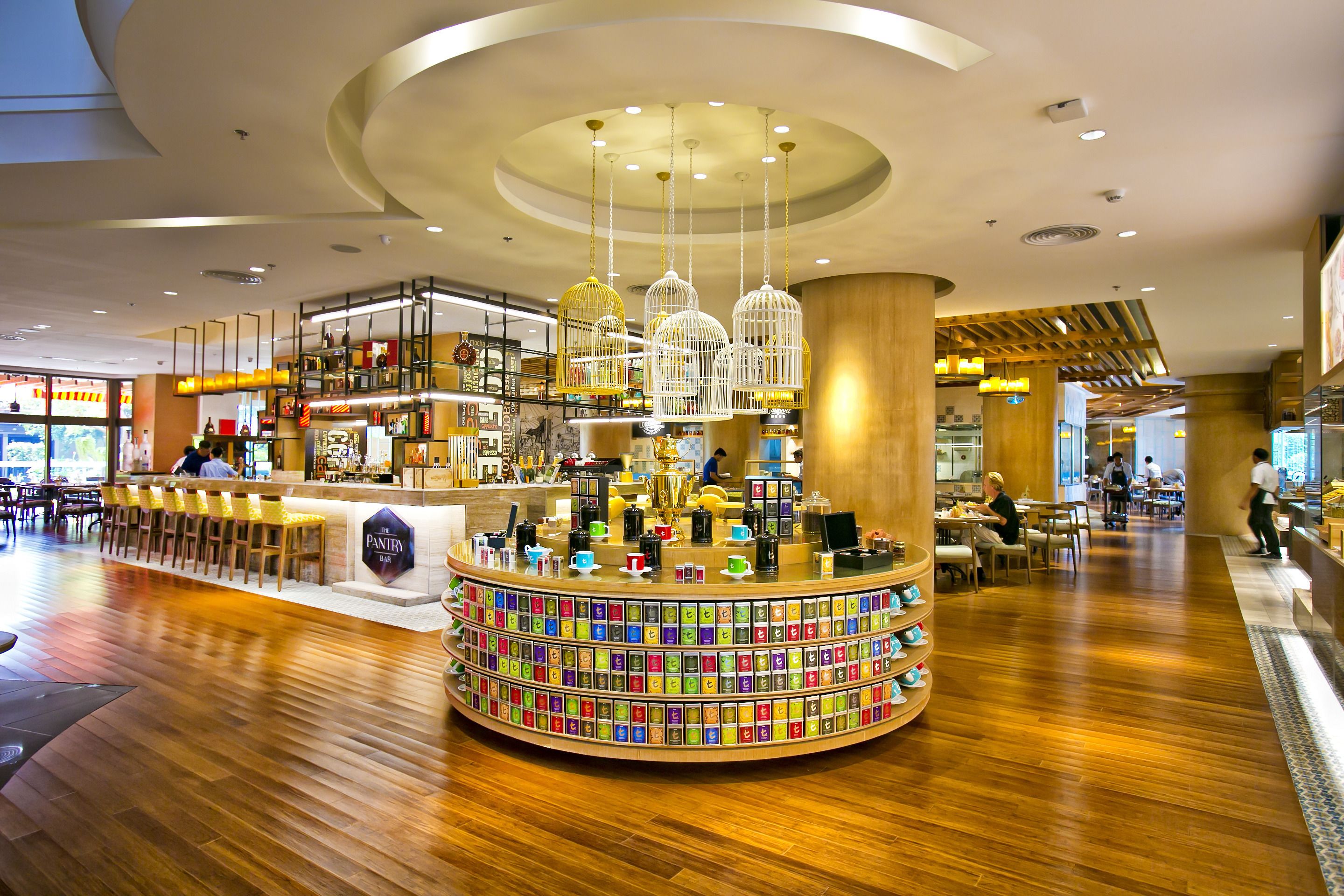 A modern interior with a central circular bar area, wooden flooring, and a variety of seating options.
