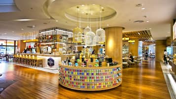 A modern interior with a central circular bar area, wooden flooring, and a variety of seating options.
