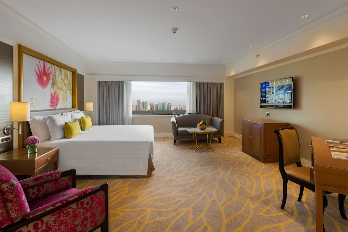 Habitación de hotel con cama, escritorio, silla, televisión y vistas a la ciudad.