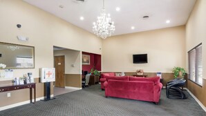 A hotel lobby with a red sofa, a chandelier, a television, and a reception desk. - Econo Lodge Inn & Suites Knoxville East (Knoxville)