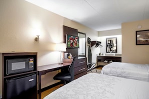 A hotel room with a desk, a television, a bed, a mirror, and a coffee maker. - Red Roof Inn PLUS+ St Louis - Forest Park/ Hampton Ave (St. Louis)