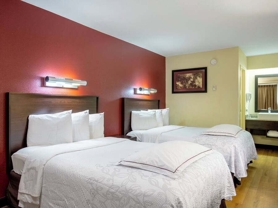 A hotel room with two beds, a mirror, and a painting on the wall.