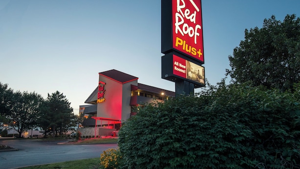 A hotel with a prominent red and white sign advertising 'Red Roof Plus' rooms.