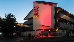 A hotel with a prominent 'Red Roof Plus' sign, a multi-story structure, and a landscaped front yard.