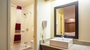 A bathroom with a bathtub, toilet, and a sink with a mirror above it.