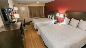 A hotel room with two beds, a desk with a television, and a minibar.