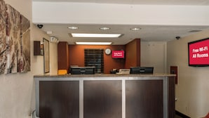 A reception desk with a clock, a sign indicating free Wi-Fi, and a security camera above.