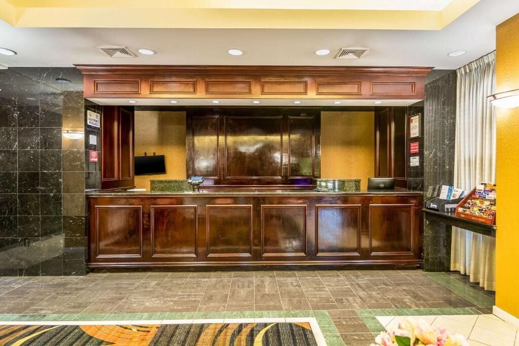 A reception area with a wooden reception desk, a flat-screen TV, and a digital display board.