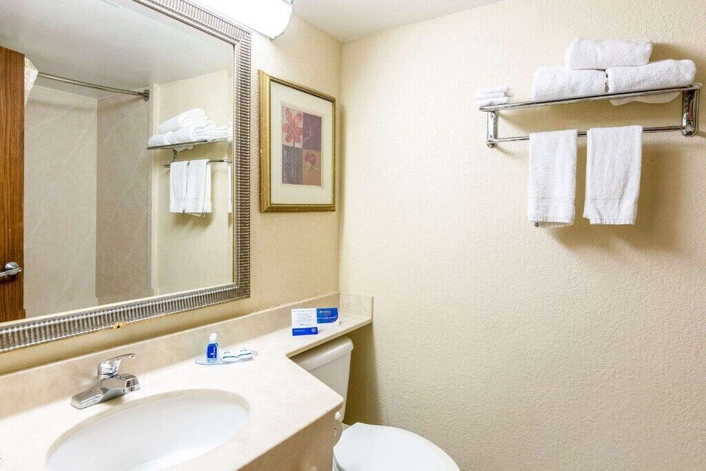 A bathroom with a sink, mirror, towel rack, and toilet.