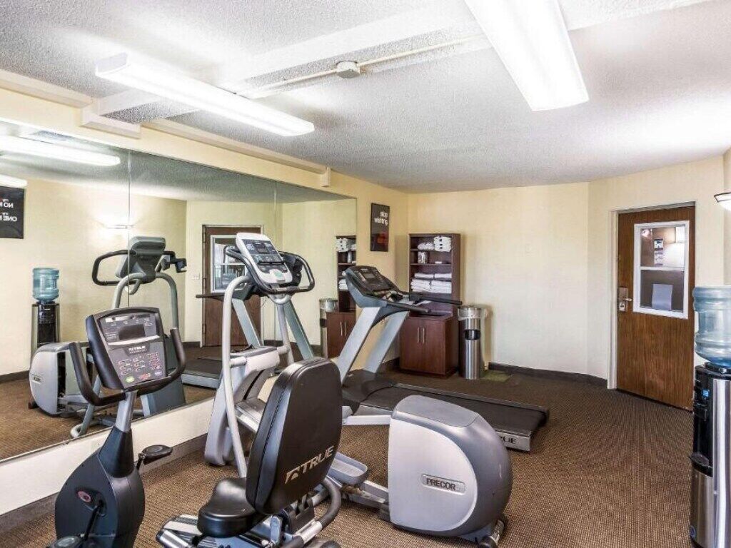 A gym with treadmills, ellipticals, and a water dispenser.