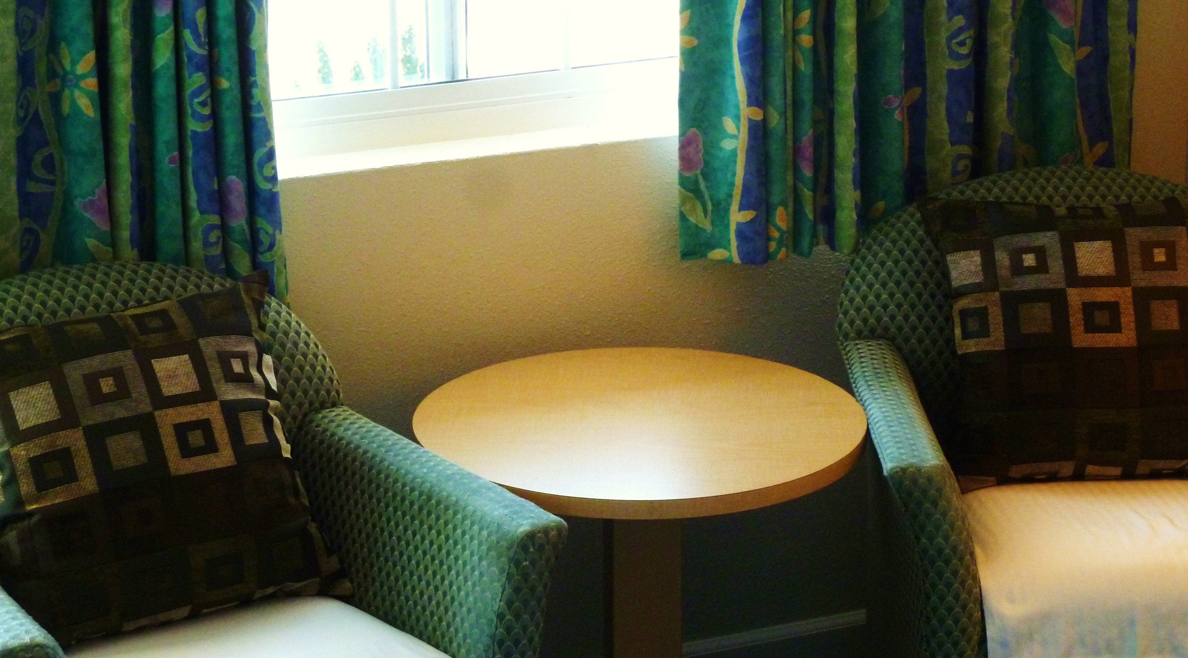 A small room with two patterned armchairs facing a round table.
