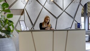 A reception desk with a geometric wall design, a potted plant, and a sign indicating a spa treatment. - Best Western Plus Nottingham Westminster Hotel (Nottingham)