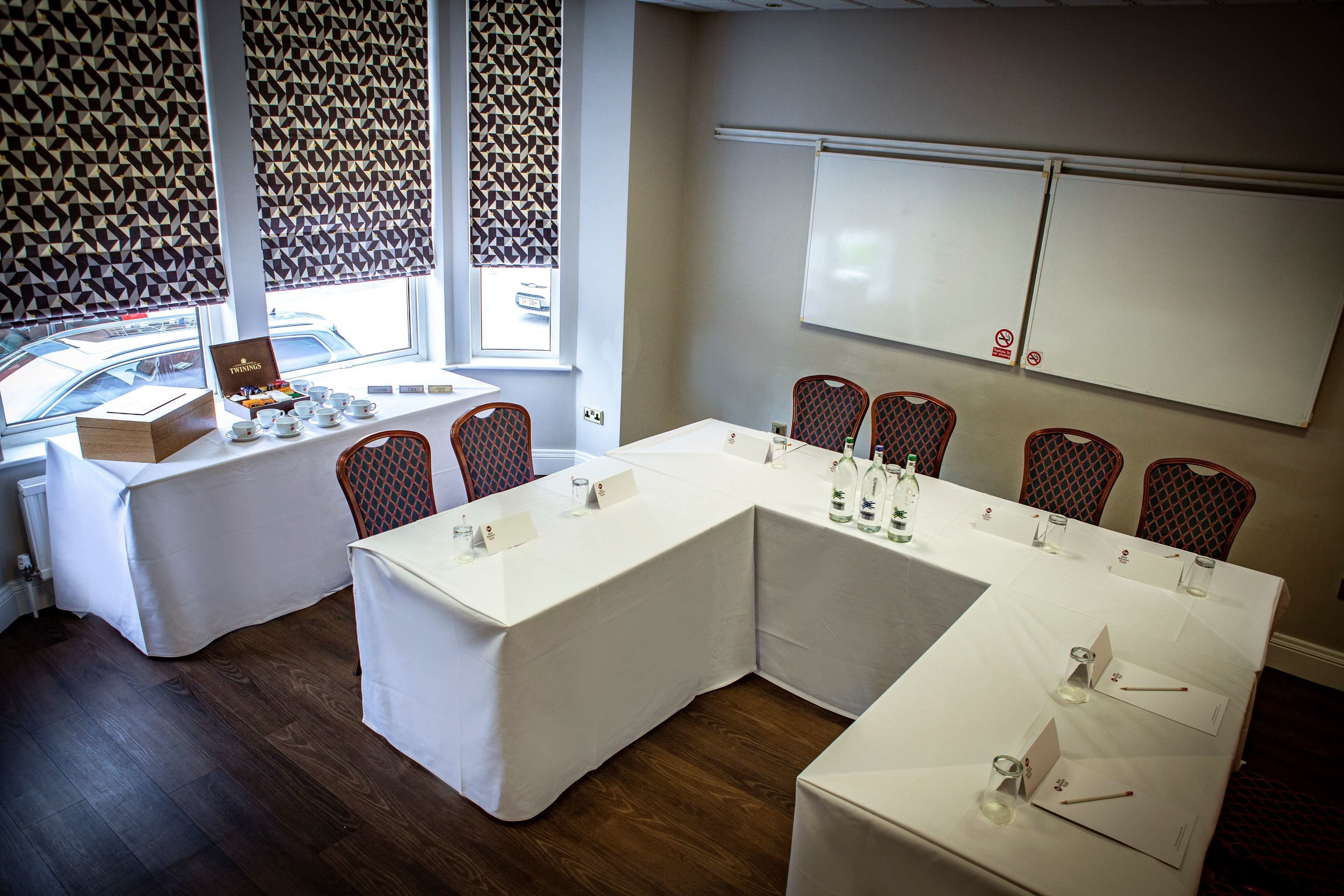 A conference room with a white table, chairs, and a whiteboard.
