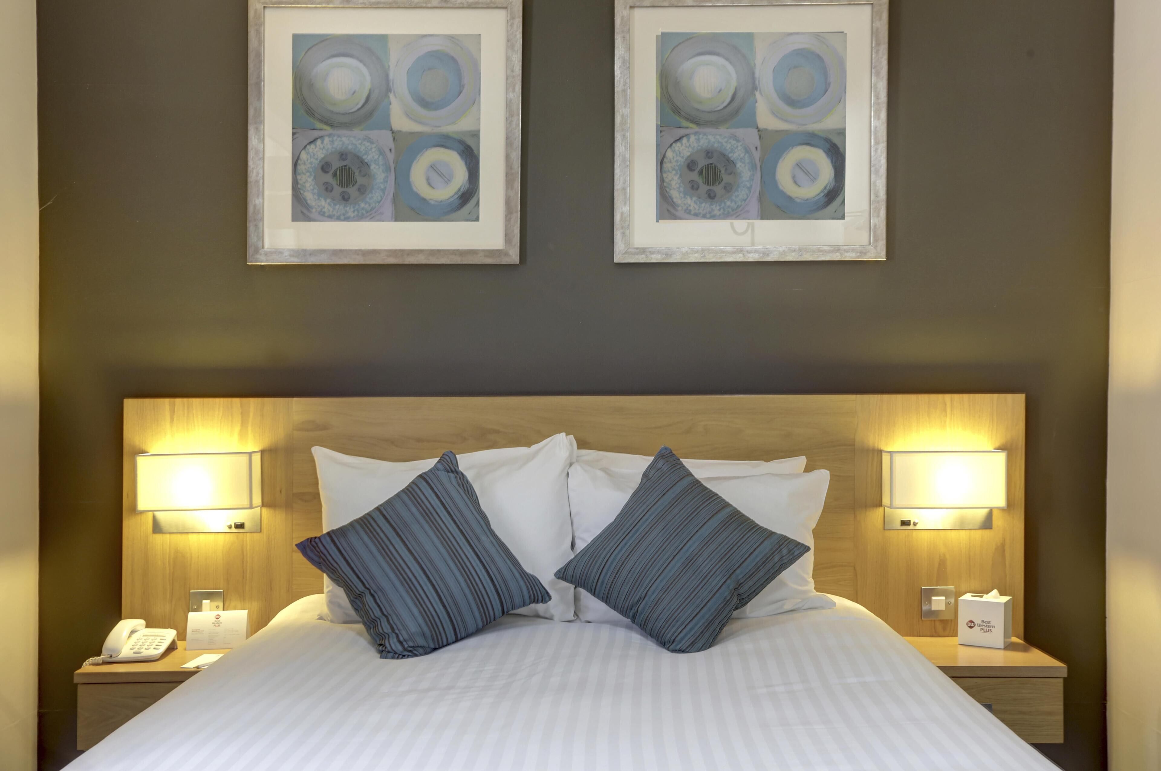 A neatly made bed with striped pillows, a wooden headboard, and two bedside lamps.